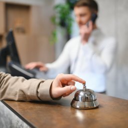 Hand of a woman using a hotel bell.