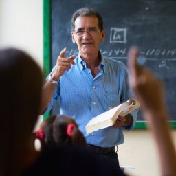 Young people and education. Group of hispanic students in class at school during lesson. Girl raising hand and asking question to teacher