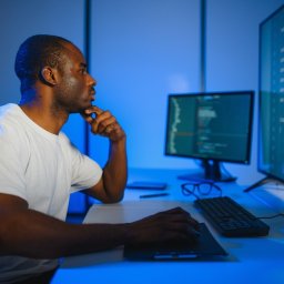 IT Programmer Working on Desktop Computer. Male Specialist Creating Innovative Software Engineer Developing App, Program, Video Game. Terminal with Coding Language. Over Shoulder